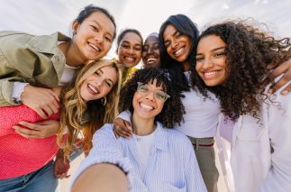 Diverse group of happy young female friends having fun taking selfie portrait together outdoors. Female friendship and youth concept.